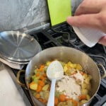 Add flour to sautéed vegetables and mix to combine for chicken pot pie recipe.