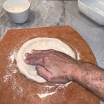 Form the pizza dough crust ring by pressing out and turning the dough.