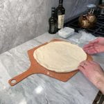 Toss the stretched pizza dough onto a floured pizza peal.