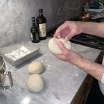 Complete pizza dough balling by pinching the dough closed at the bottom of the pizza dough ball.