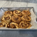 Place cut cinnamon rolls in a buttered baking pan.