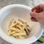 Potato slices placed in large mixing bowl to soak and rinse.