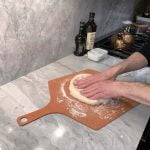 Punching out a pizza dough ball.