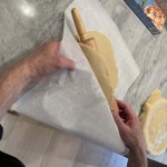 Roll pie dough for chicken pot pie onto a rolling pin to transfer to a pie pan.