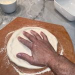 Gradually stretch and form the pizza from the dough ball using your fingers and hand and turning the dough as you stretch it.