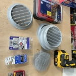 Supplies and tools for replacement of the Airstream AC duct registers including: 5" aluminum grilles with screens removed, 1/8" Pop Toggle drywall anchors, #8 ribbed plastic anchors, stainless steel #8 by 3/4" screws, a Philips screwdriver and drill with a 3/16" bit.